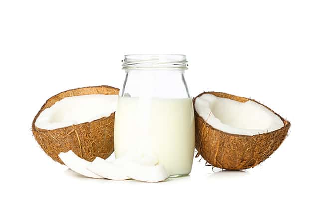 A Jar of coconut milk with two coconut half shells